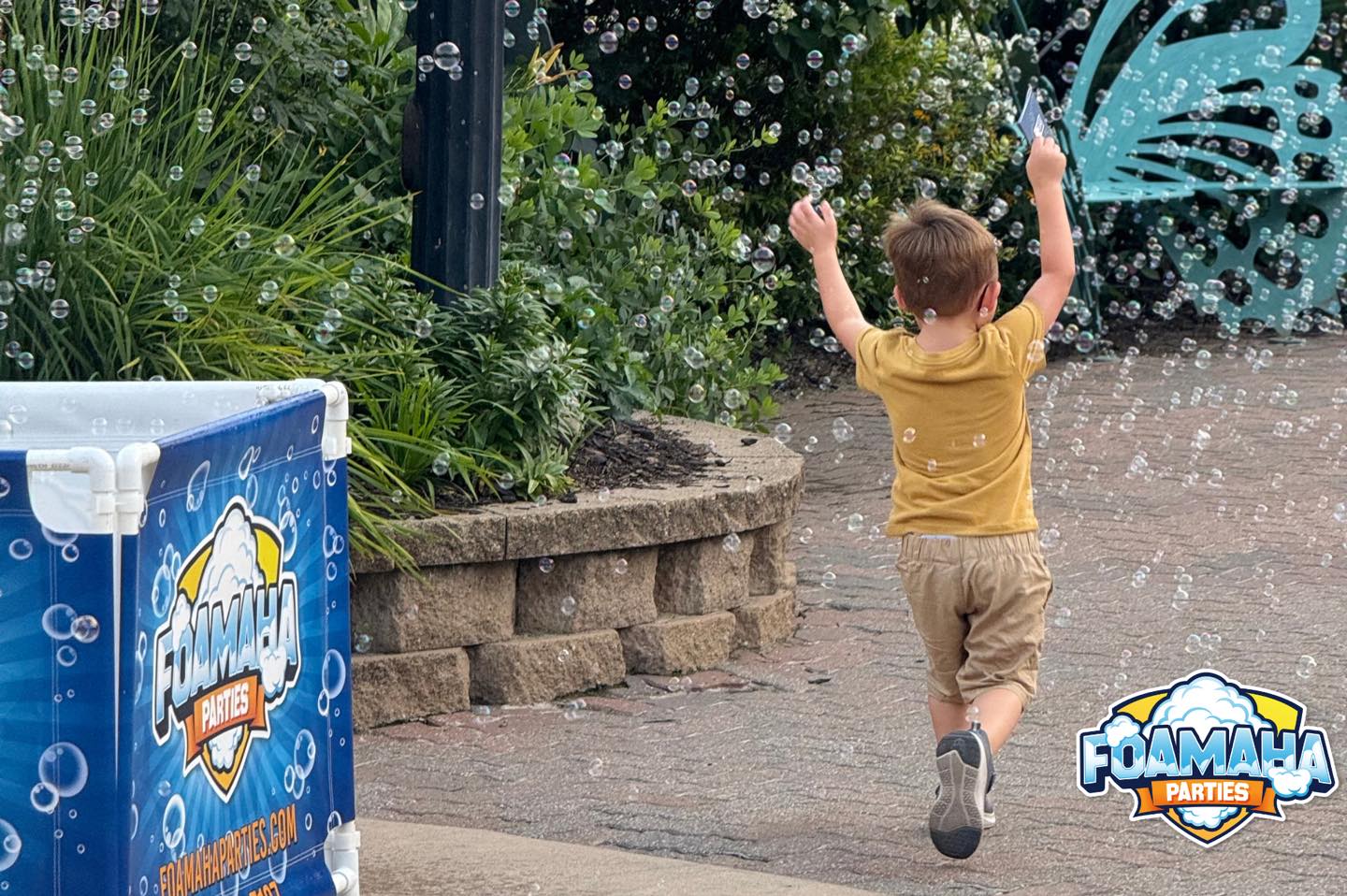Little boy chasing bubbles next to a Foamaha bubble machine