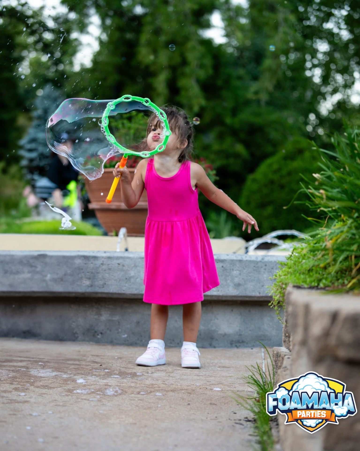 Little girl in a pink dress blowing a giant bubble