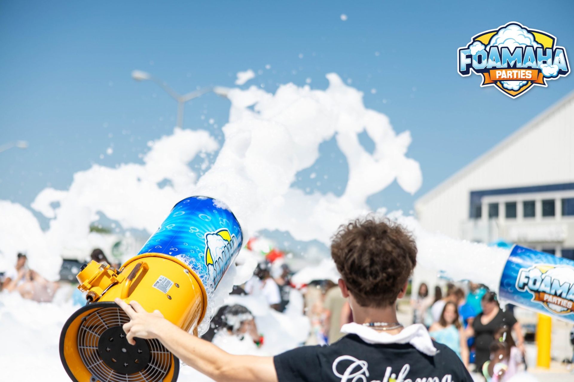 Foamaha operator firing a foam cannon into a bright blue sky