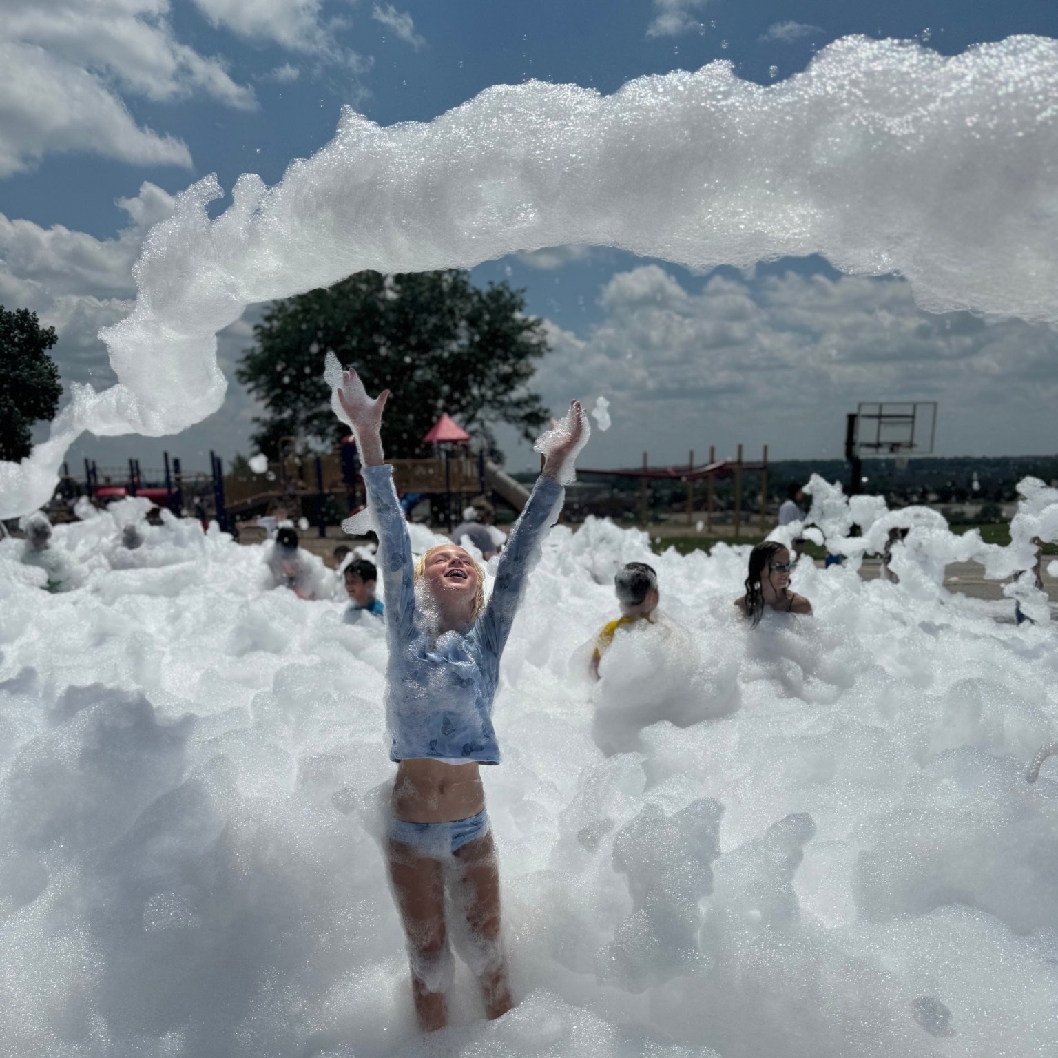 Girl reaching up as a giant arch of foam soars overhead