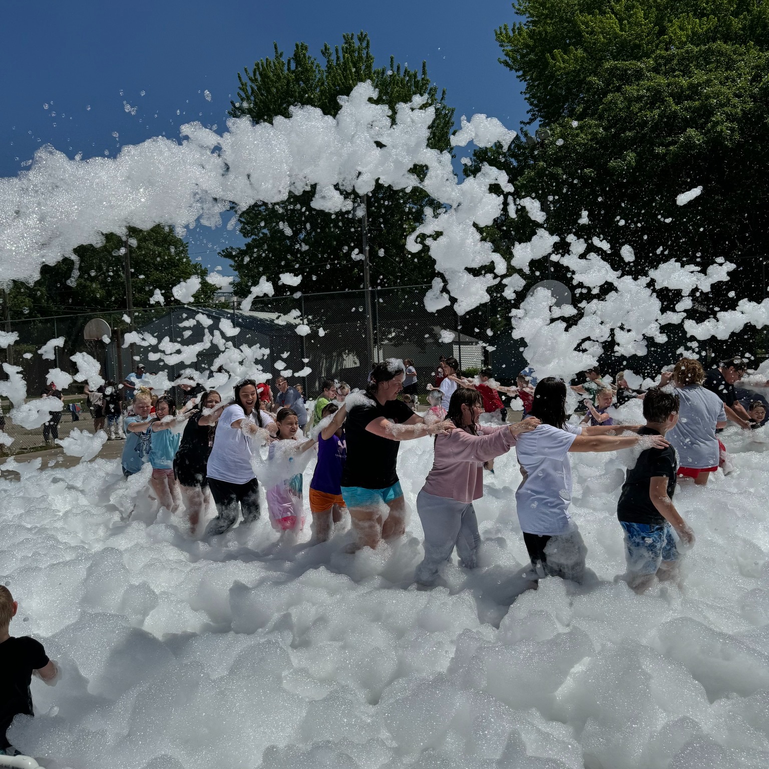 Group doing a conga line in mountains of white foam
