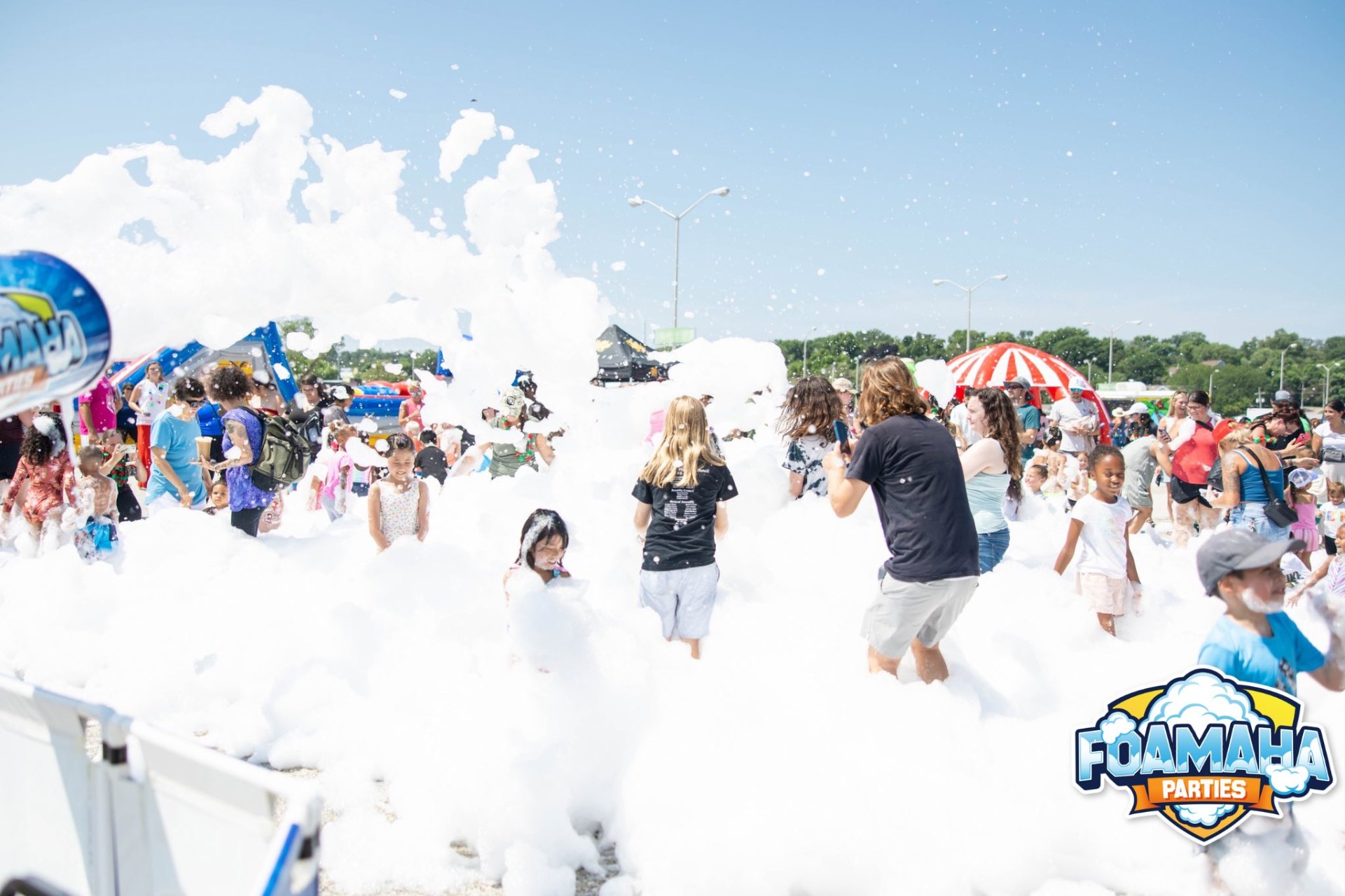 Massive festival crowd surrounded by white foam at a Foamaha event